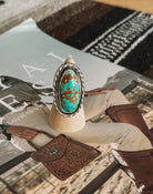 Turquoise and brown western boho ring with silver setting on wooden display, magazine background