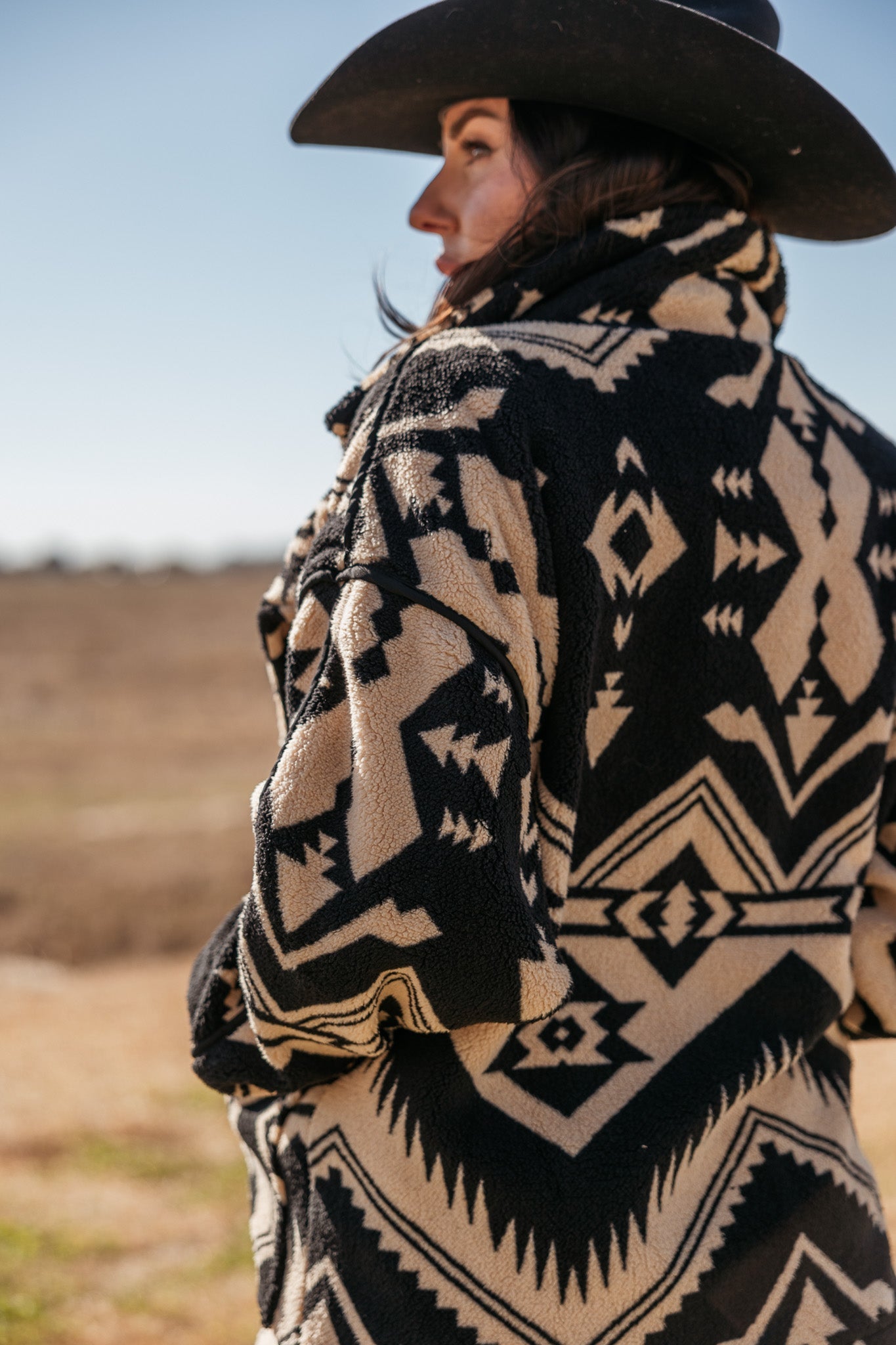 Woman in black western hat and Aztec print sherpa jacket outdoors