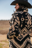 Woman in black western hat and Aztec print sherpa jacket outdoors