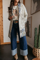 Woman in a western boho outfit with patterned jacket, horse sweater, wide-leg jeans, and cowboy boots