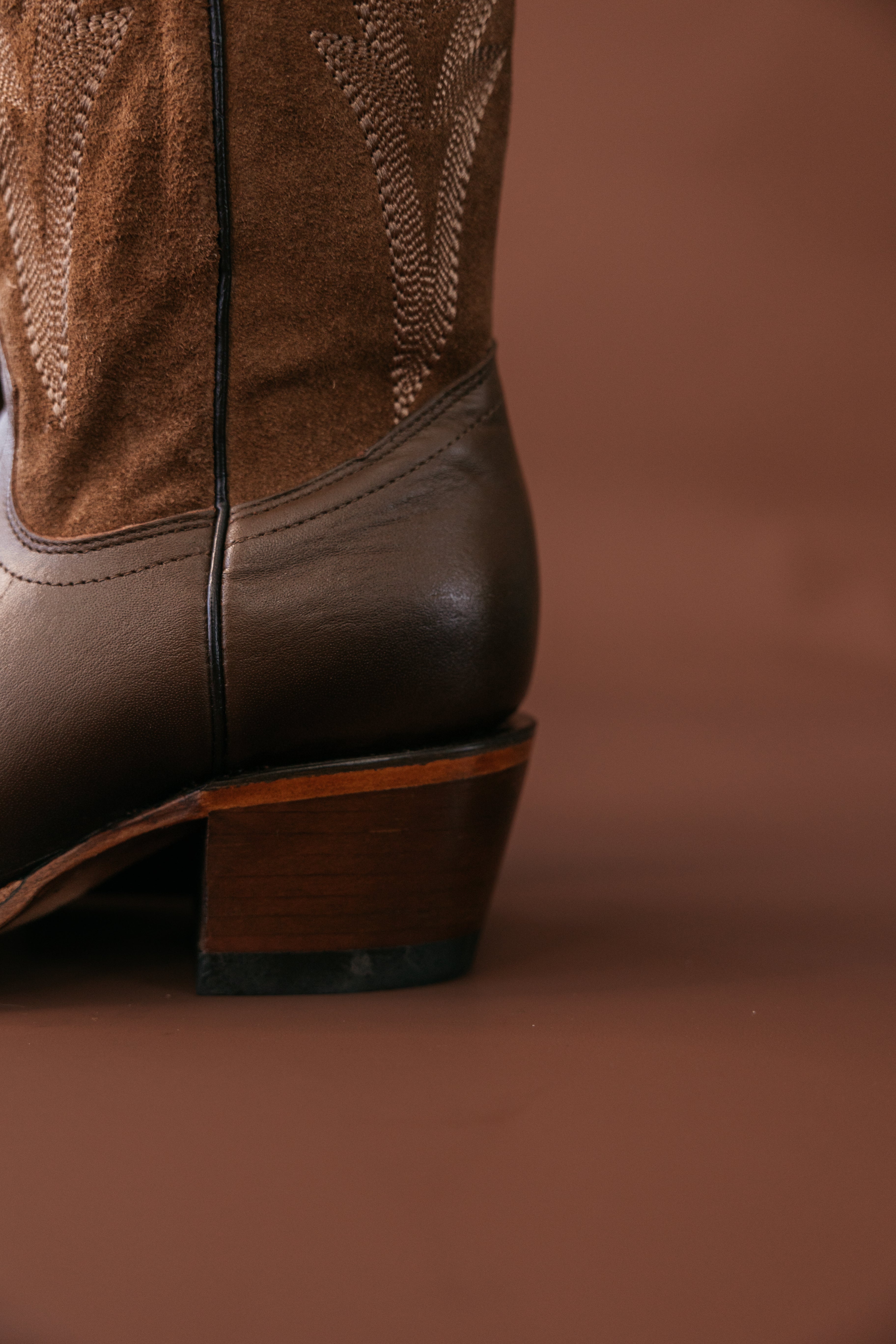 Close-up of brown leather and suede western cowboy boot with embroidered detail