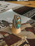 Oval turquoise and brown gemstone western boho ring with silver rope detailing on display