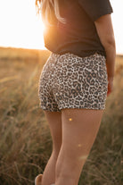 Person wearing leopard print shorts in a field with warm sunlight