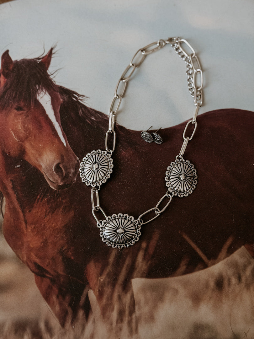 Silver western concho necklace and earrings set on a horse-themed background, boho jewelry