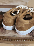Close-up of brown western-style sneakers with white soles and laces, perfect for boho outfits