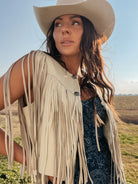 Woman in a cowgirl hat and fringe suede vest wearing a western boho dress outdoors