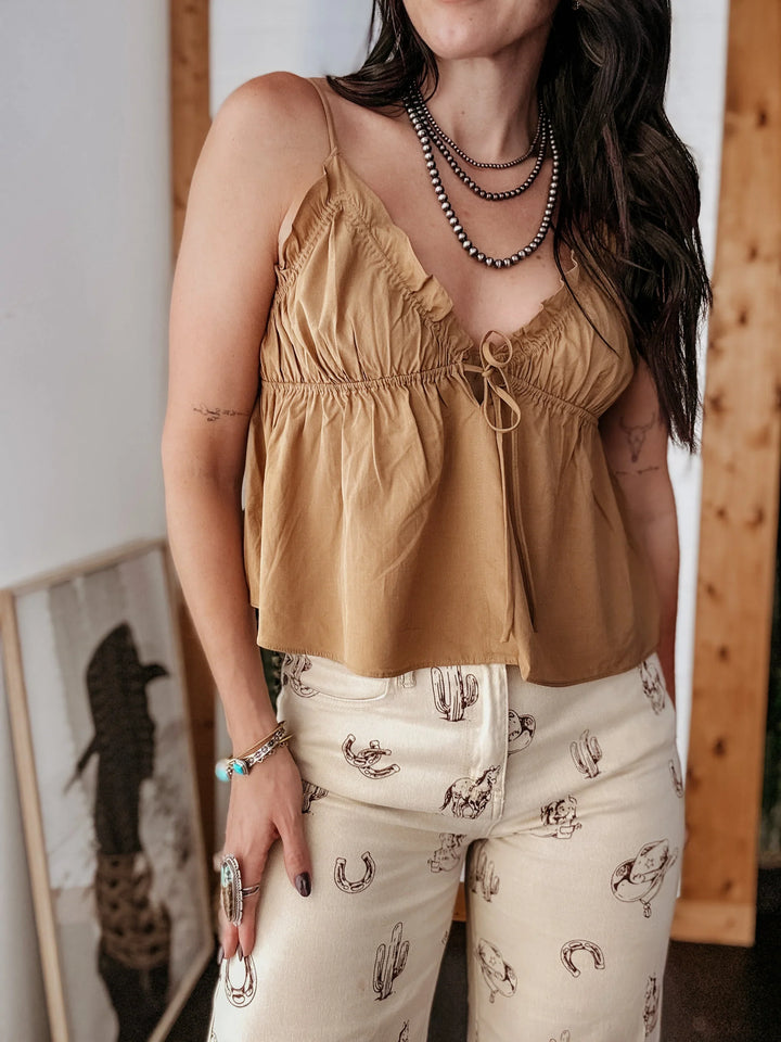 Woman wearing a mustard yellow top and patterned pants indoors.