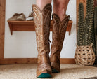 Close-up of brown embroidered cowboy boots in western boho room with cactus decor