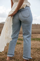 Woman in light wash western jeans and flowy white blouse outdoors on grass field