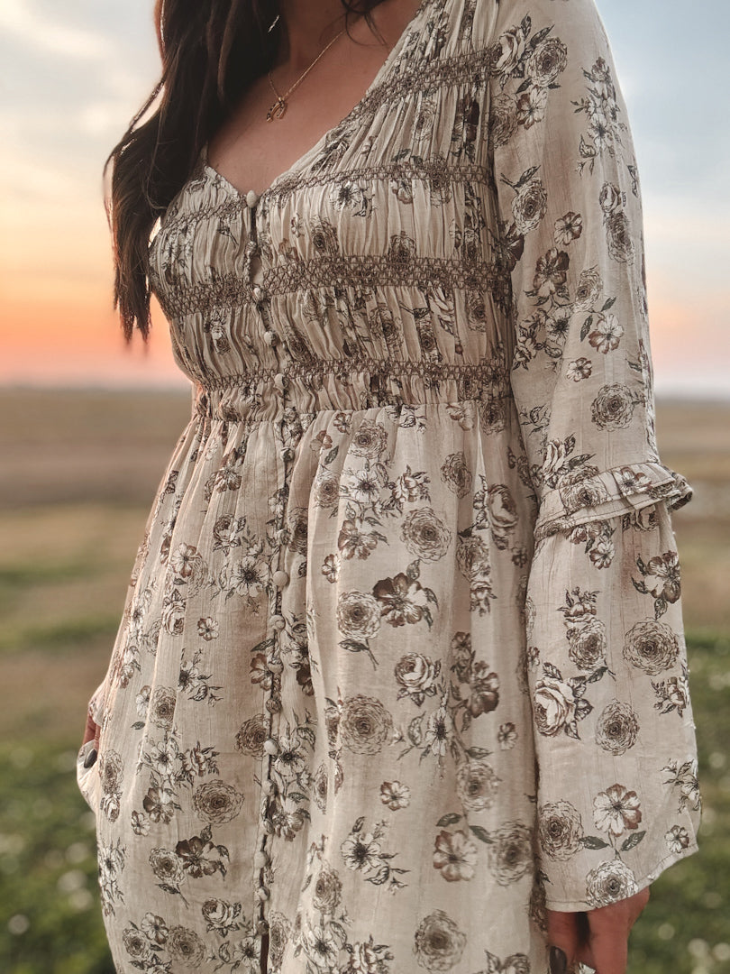 western boho dress in white with sage floral print with a slit and beige knee-high cowgirl boots close up. model in field