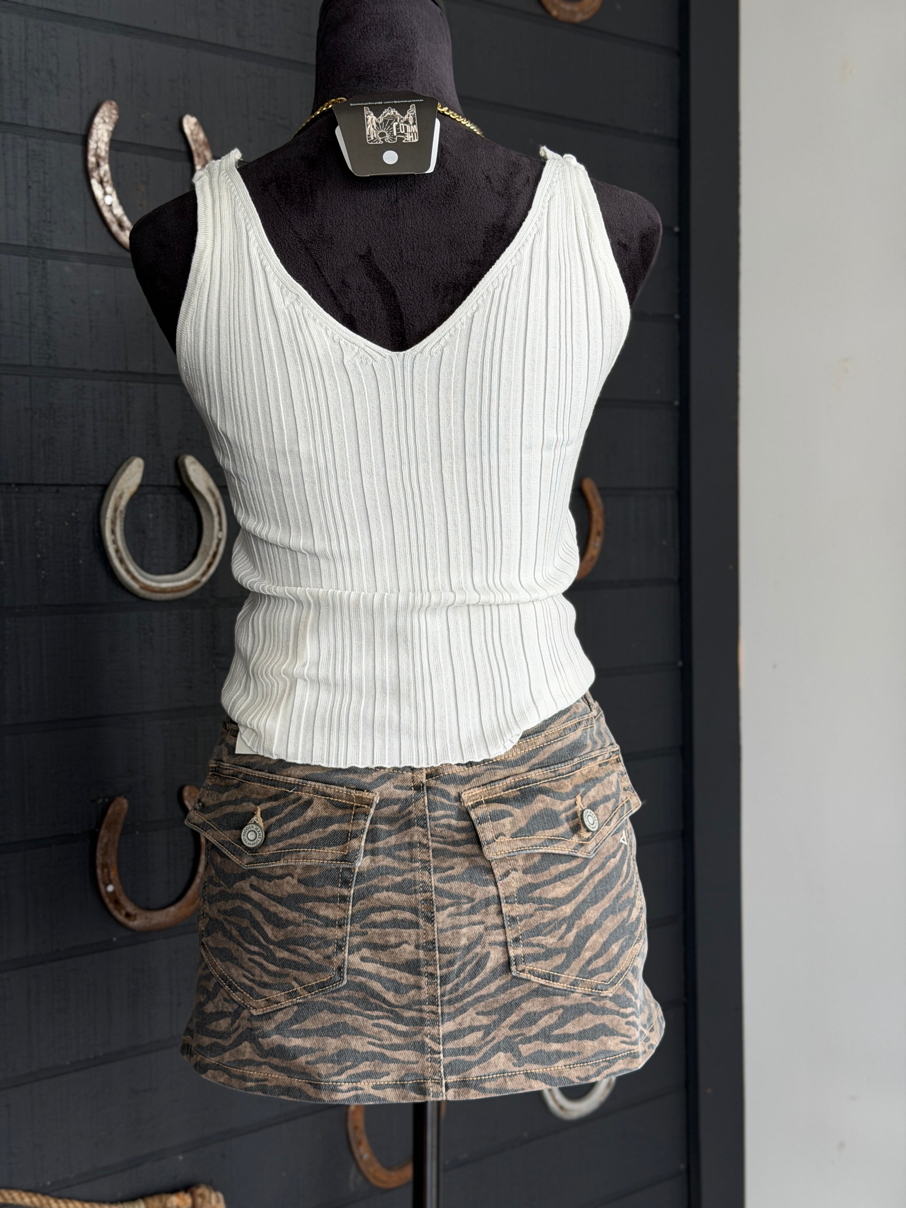 White ribbed tank top and zebra print skirt on a mannequin against a dark background