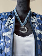 Western boho outfit with blue floral jacket, white top, and horseshoe necklace