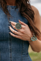 Woman wearing a turquoise western statement ring and cuff bracelet with denim dress