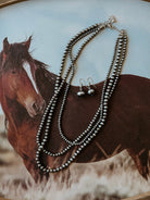 Thunderbird pendant chain necklace displayed on wooden slab with serape fabric underneath - The Wild J