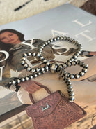 Thunderbird pendant chain necklace displayed on wooden slab with serape fabric underneath - The Wild J