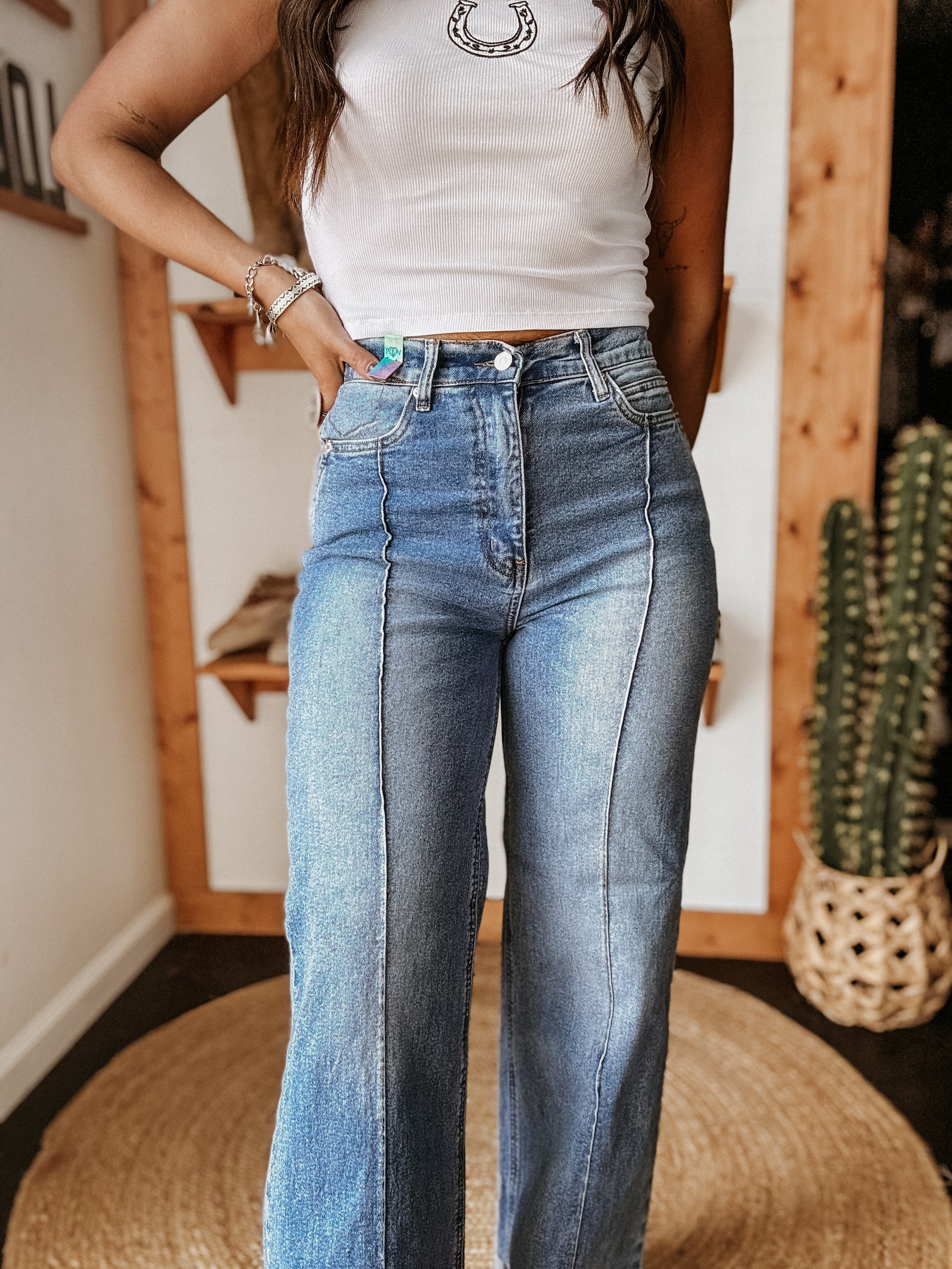 Woman wearing high-waisted wide leg jeans and a white western tank top with a horseshoe design