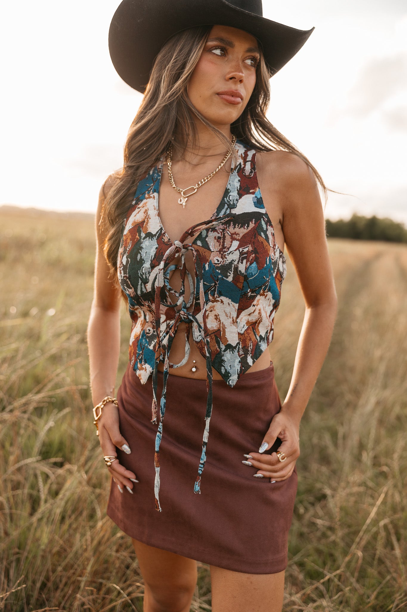 women wearing tie front halter top with horse pattern and a Burgundy skirt standing in a field. 