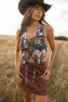 women wearing tie front halter top with horse pattern and a Burgundy skirt standing in a field. 