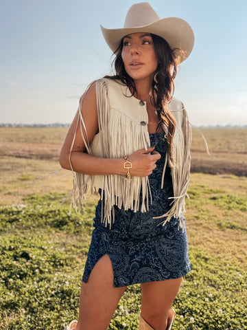 Woman wearing a fringe vest and cowboy hat in an open field