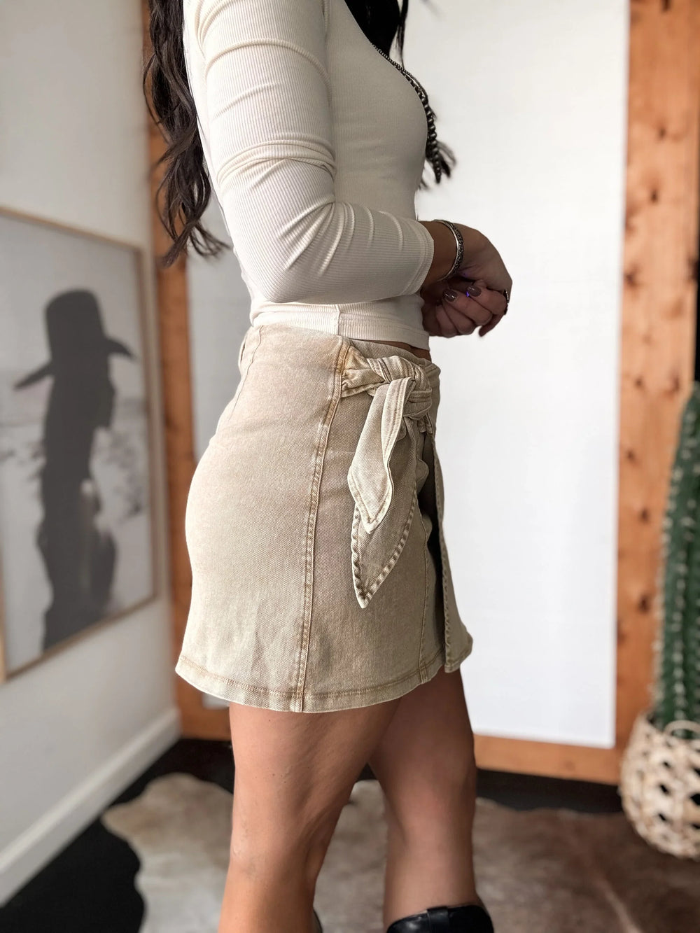 Person wearing a beige denim apron in a room with wooden walls and a painting.