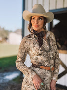 Woman in western boho dress, cowboy hat, and scarf posing outdoors for cowgirl fashion