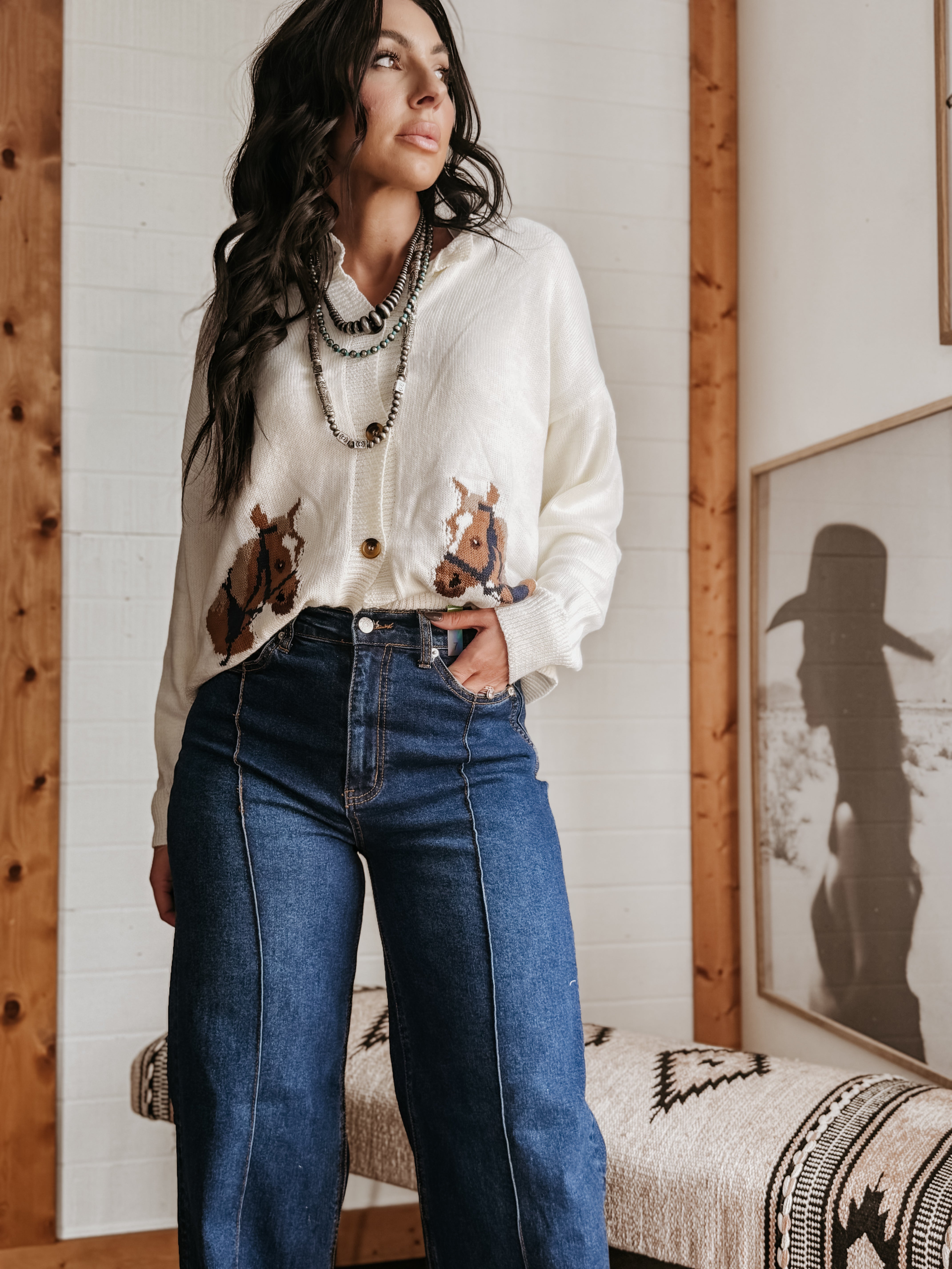 Woman in a western boho outfit with cow print cardigan, layered necklaces, and wide-leg jeans