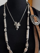 Thunderbird pendant chain necklace displayed on wooden slab with serape fabric underneath - The Wild J