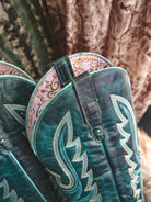 Close-up of teal western cowgirl boots with decorative stitching and embossed patterns