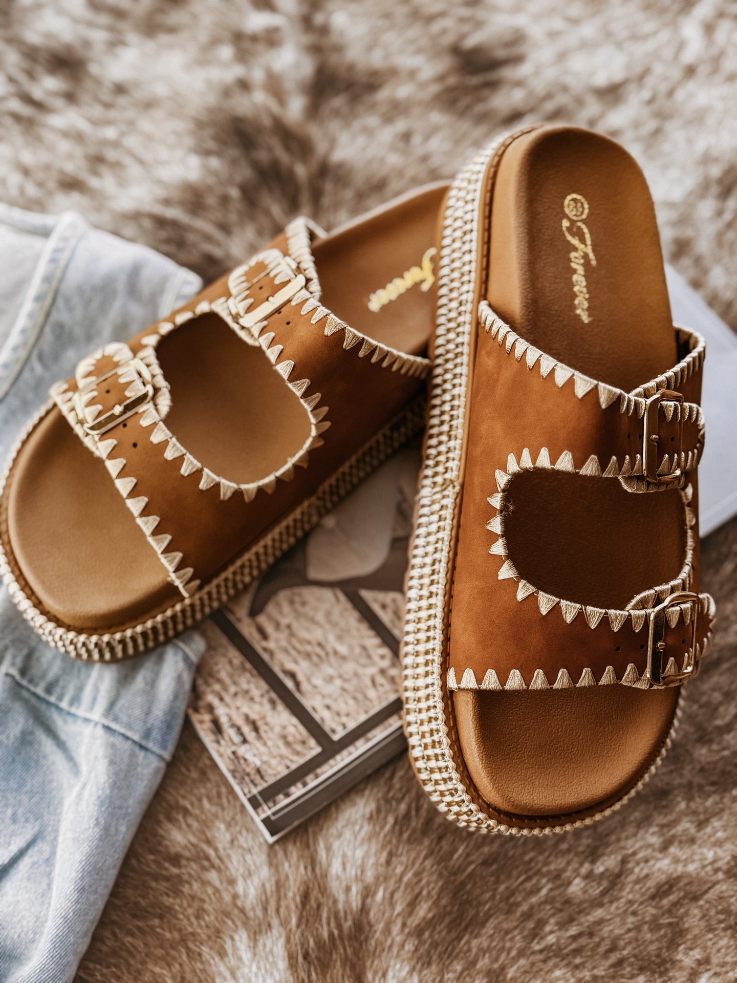 Camel platform sandals featuring two stitched buckle straps with gold adjustable hardware, a braided raffia-style platform, textured sole for added grip, and a soft cushioned insole for comfort.