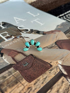 Western turquoise statement ring with silver setting on cowgirl fashion magazine, tooled leather bag