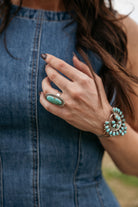Woman wearing denim dress, turquoise statement ring and western turquoise bracelet