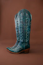Teal embroidered western cowgirl boots with pointed toes and block heels on brown background