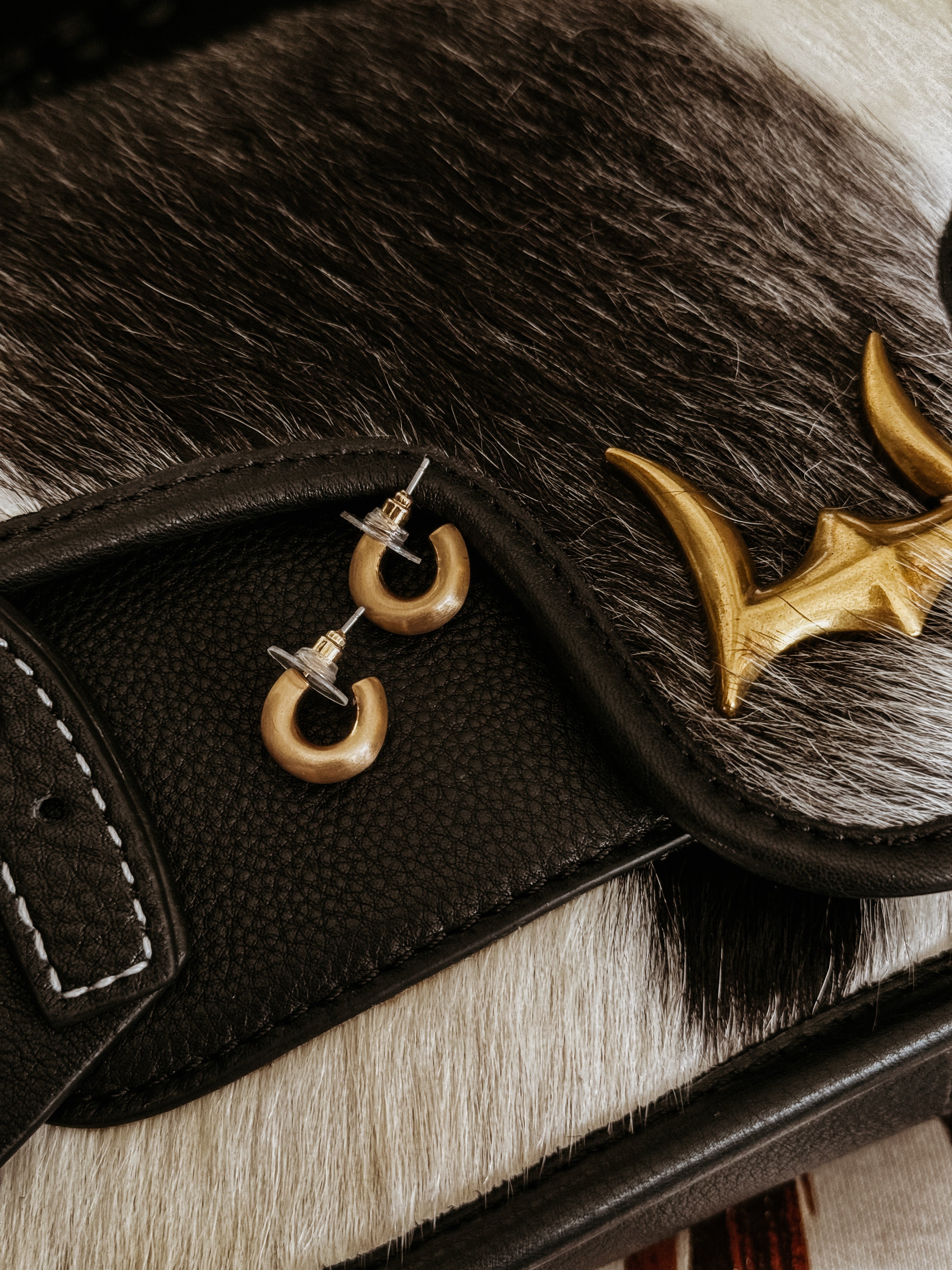 Western boho hoop earrings on black leather and cowhide bag with gold bullhorn detail