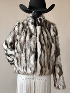 Western faux fur jacket with brown and white stripes, paired with a cowboy hat and fringe skirt