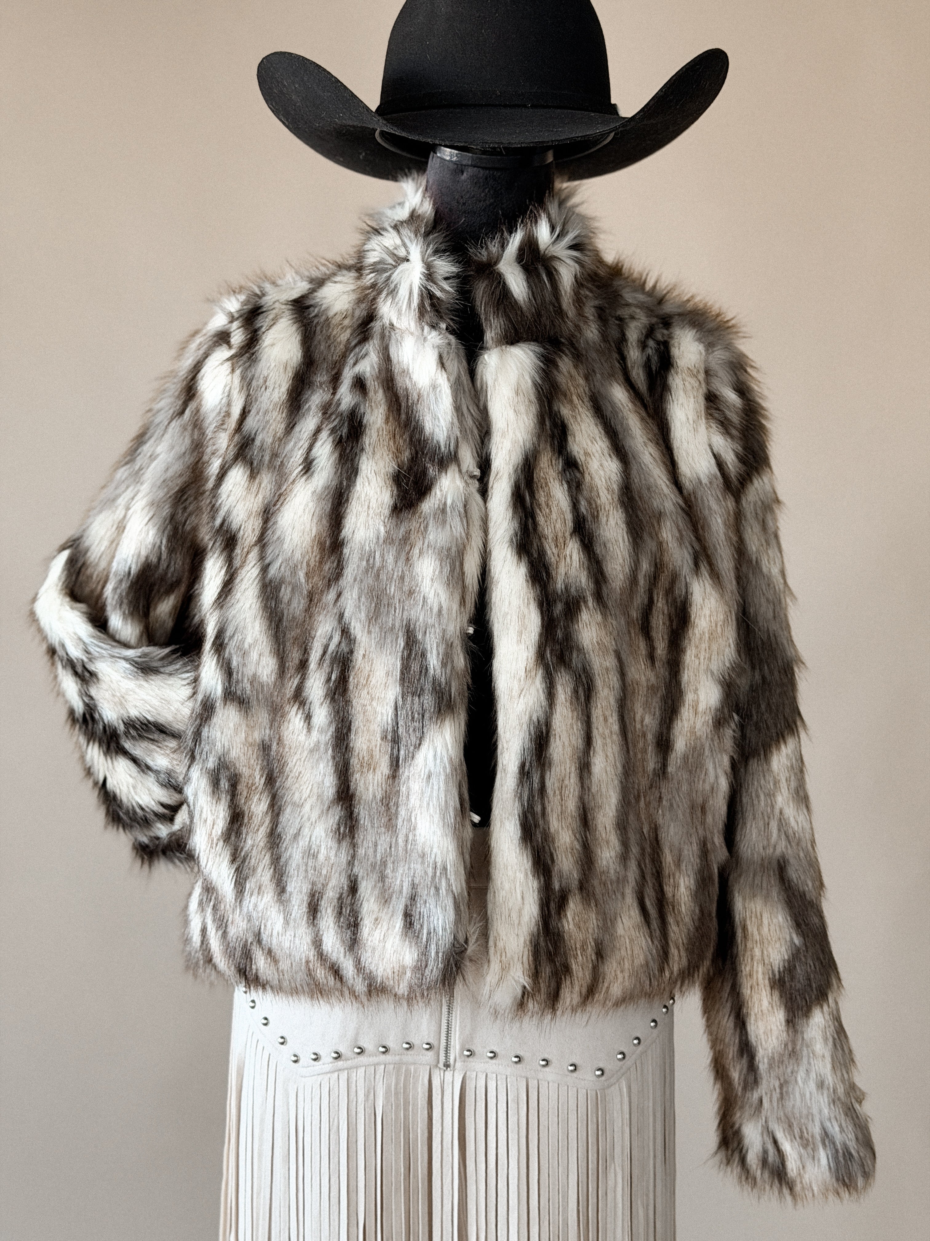 Western faux fur jacket with brown and white stripes, paired with a cowboy hat and fringe skirt