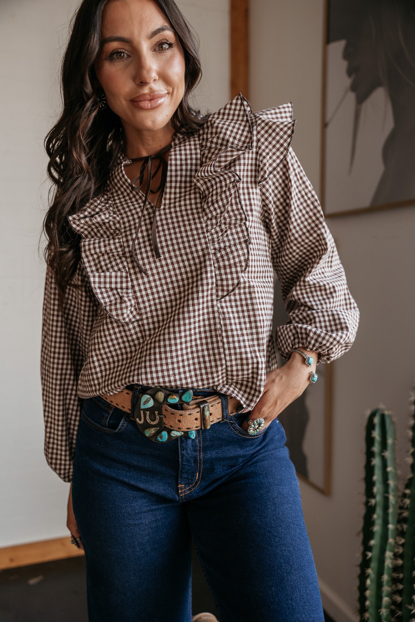 Woman in western boho outfit with ruffle gingham blouse, turquoise jewelry, denim jeans