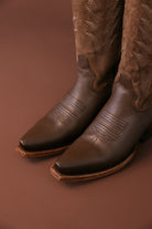 Close-up of brown leather and suede western cowboy boots with embroidered details