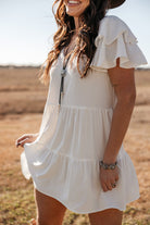 Woman wearing a white ruffle sleeve western boho dress with silver jewelry outdoors