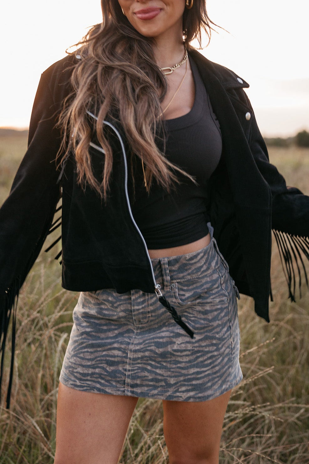 Woman in a cowboy hat and black jacket standing in a field