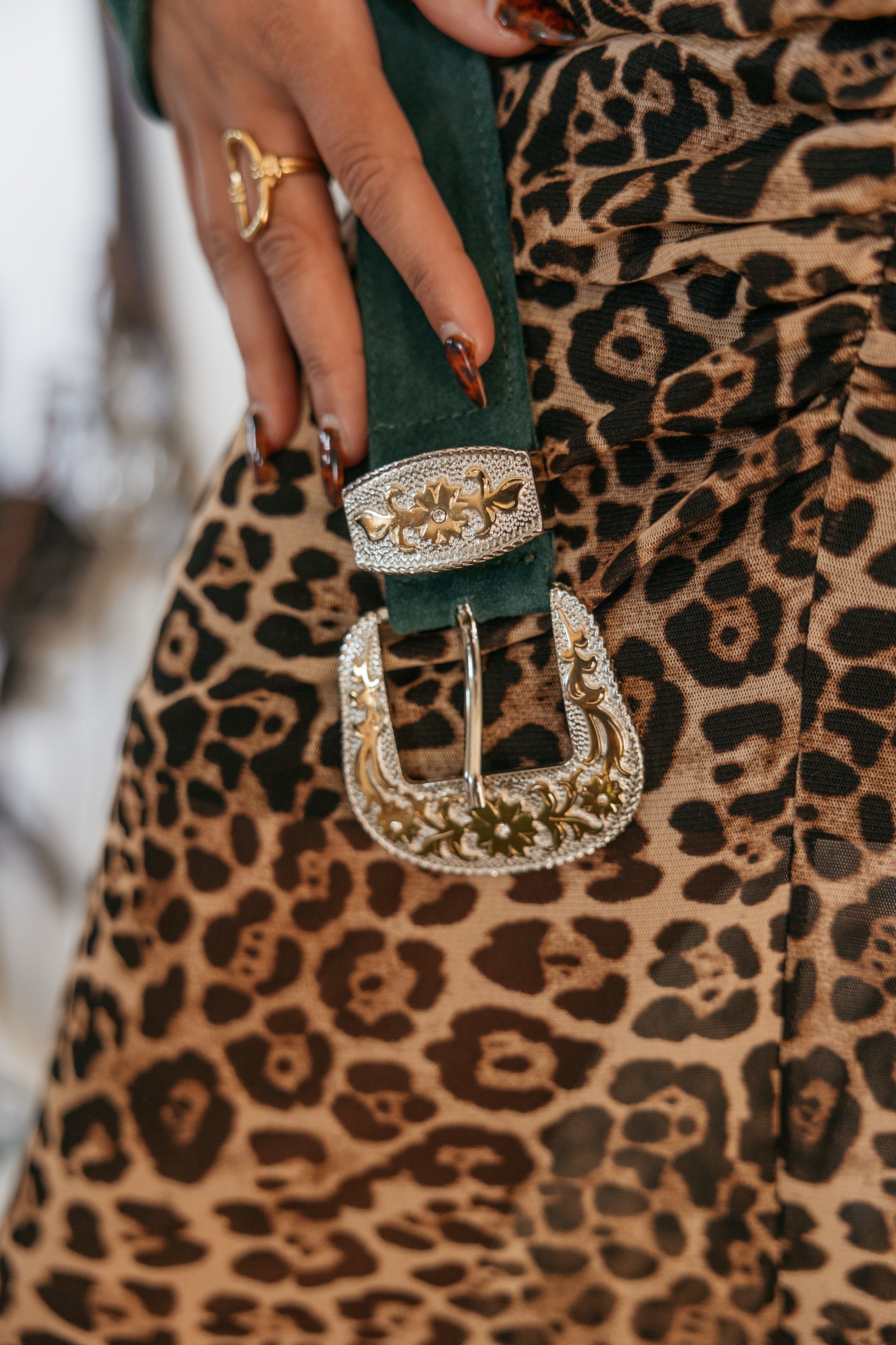 Western engraved belt buckle on green suede, paired with leopard print skirt