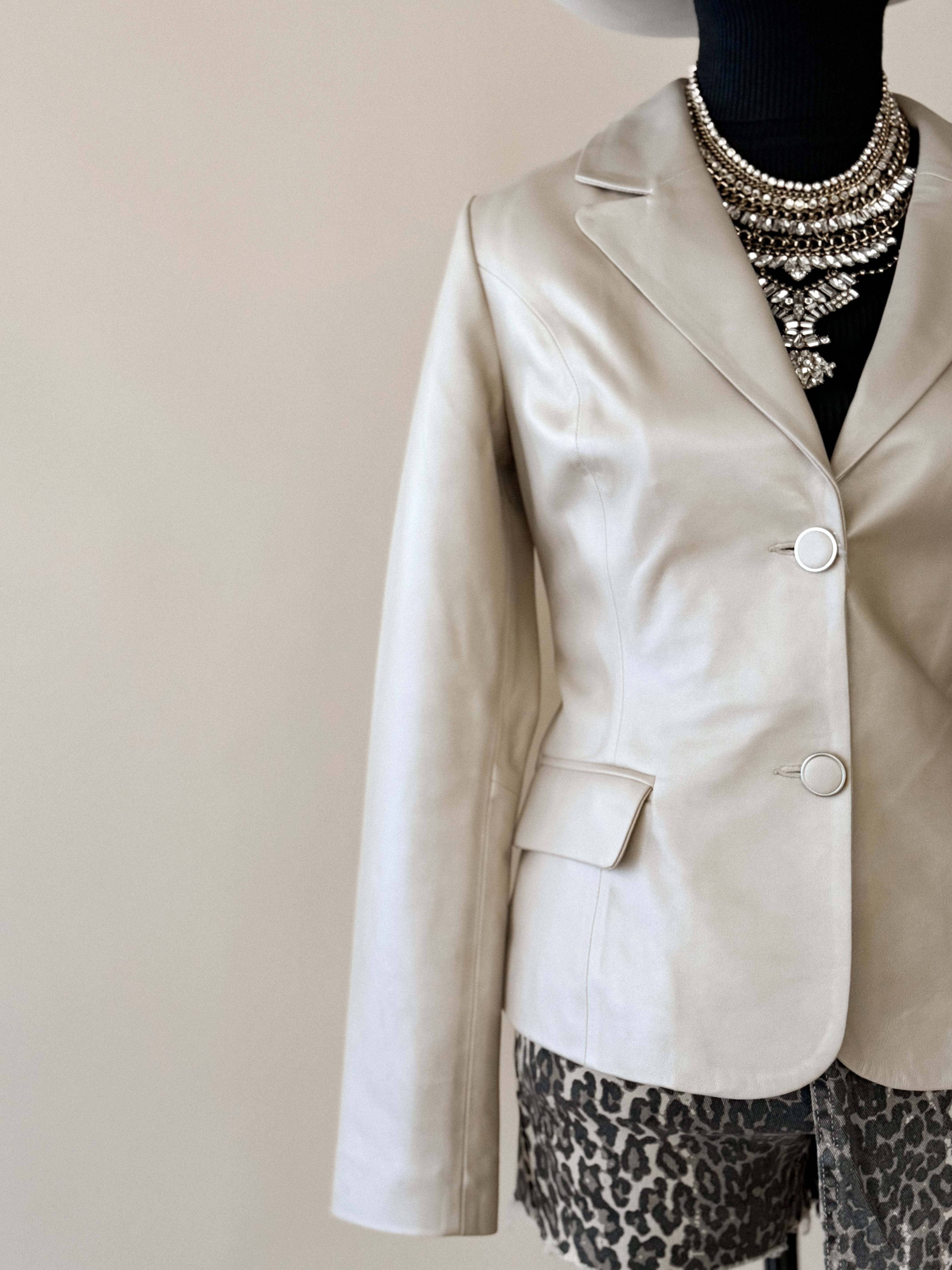 Cream western blazer with statement necklace, paired with leopard print shorts and black turtleneck