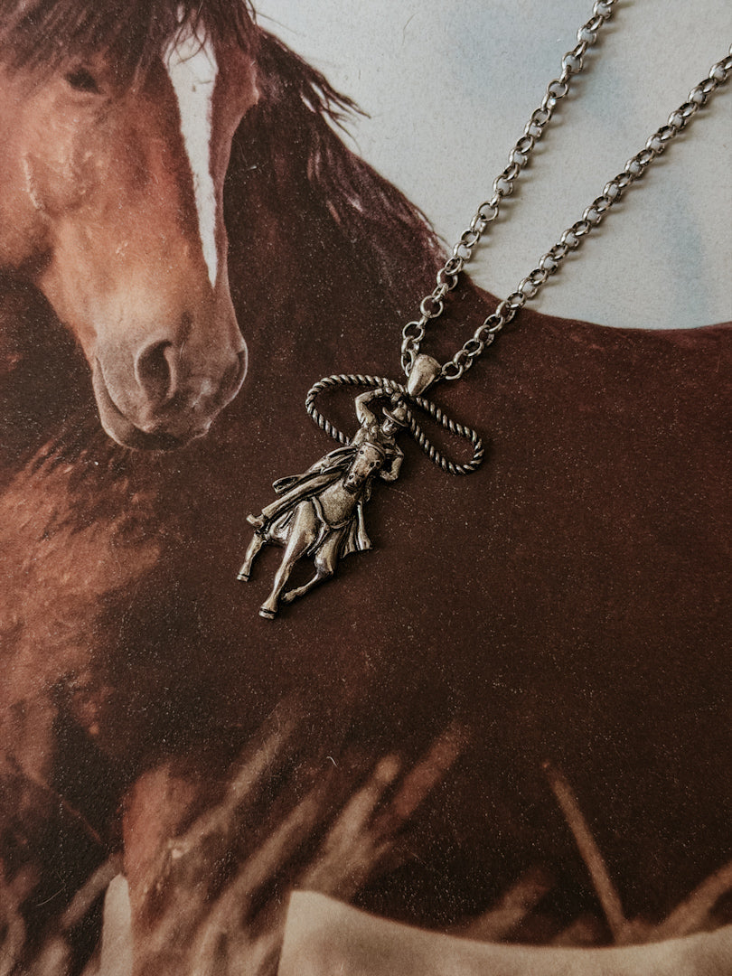 Western cowgirl necklace with lasso pendant on horse background, boho rodeo jewelry