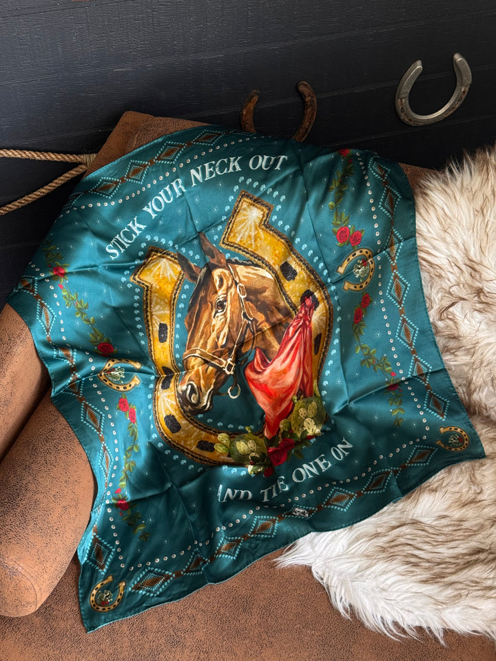 Teal bandana with horse and horseshoe design worn by a horse, with a dark background.