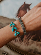 Woman wearing turquoise western bracelet and silver floral concho bracelet, horse art background