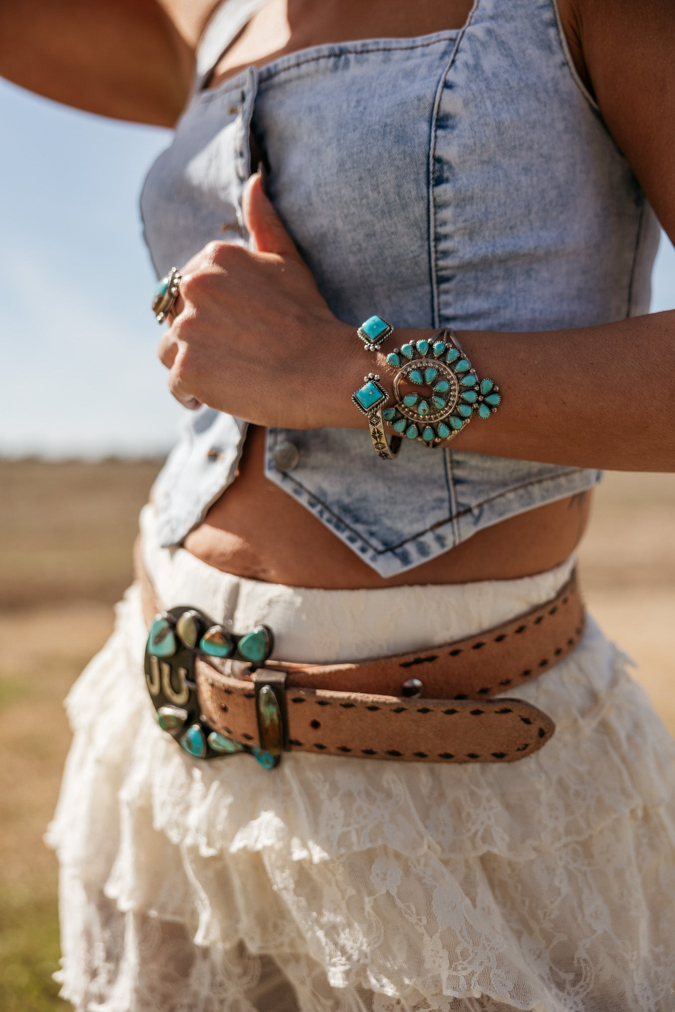 Woman in denim crop top and lace skirt with turquoise western jewelry and belt, boho cowgirl style