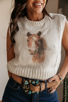 Woman in white knit horse sweater, western belt with turquoise, and boho jewelry