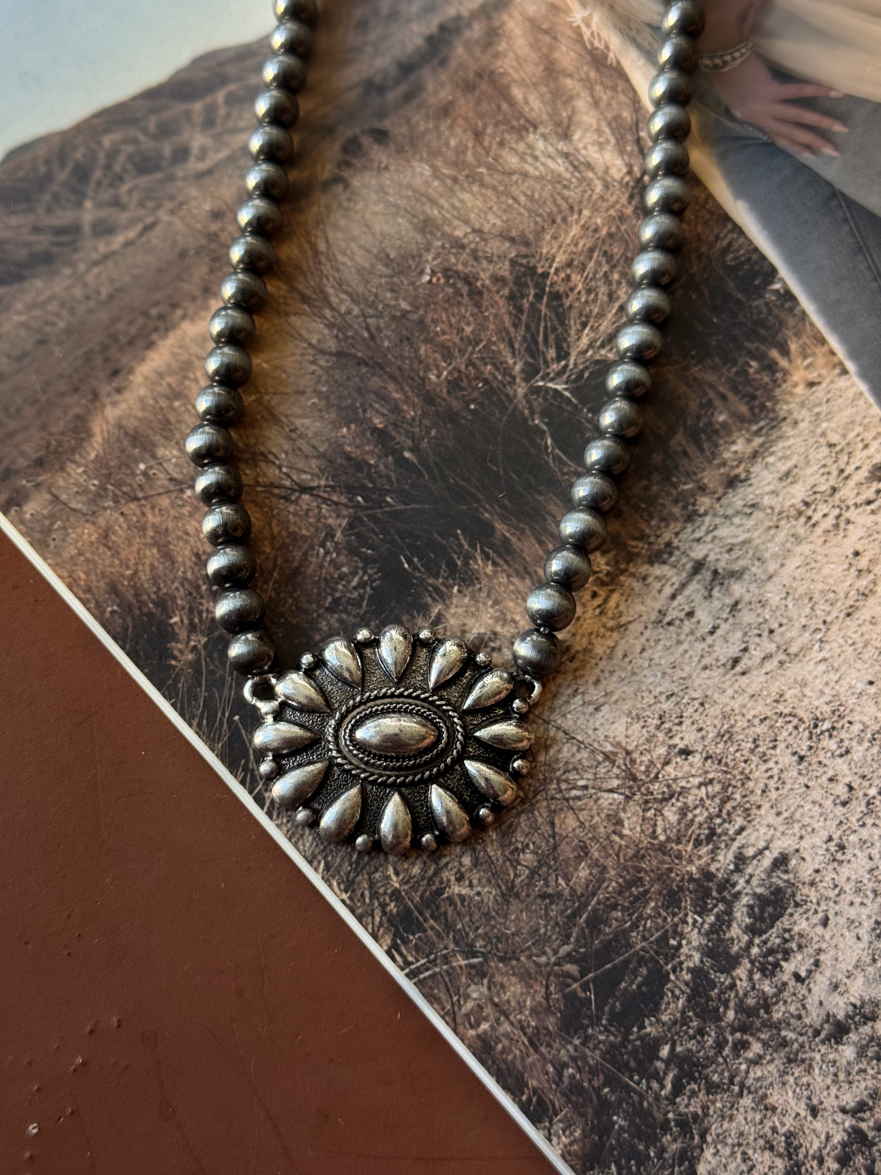 Thunderbird pendant chain necklace displayed on wooden slab with serape fabric underneath - The Wild J