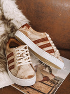 Tan and brown western sneakers with embroidered details on a faux fur rug and magazine.