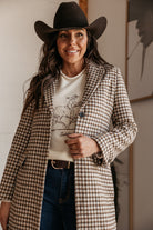 Woman in western boho outfit with plaid coat, cowboy hat, and graphic rodeo sweater
