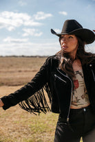 Woman in black fringe western jacket and cowboy hat outdoors, western boho outfit style